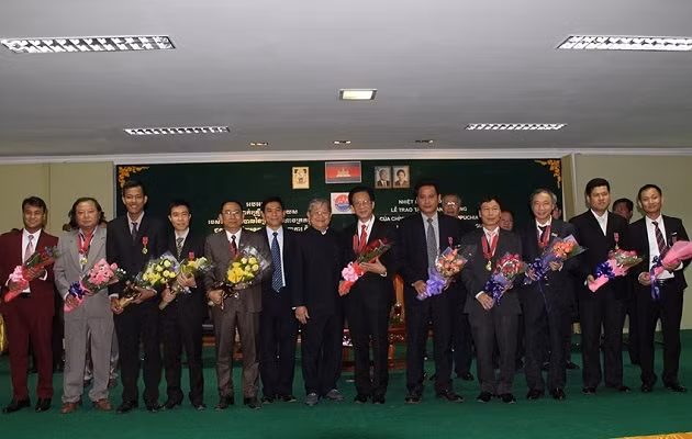 Bộ trưởng Thông tin Campuchia Khieu Kanharith chụp ảnh lưu niệm cùng các cán bộ Việt Nam được nhận Huân chương.