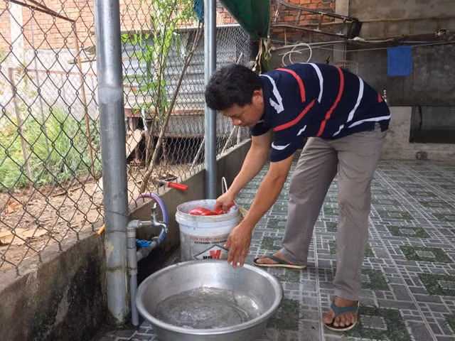 Anh Phạm Thanh Bình phải đi xin nhờ nước sinh hoạt của một hộ dân khác để sử dụng khi hệ thống nước của gia đình bị cắt.