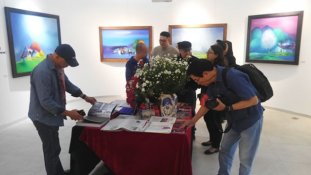 Khách tham quan tại triển lãm và xem sách của họa sĩ.
