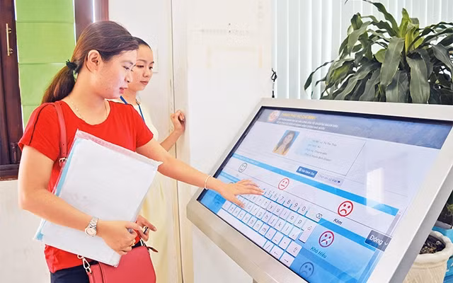 Cán bộ UBND huyện Bình Chánh hướng dẫn người dân tra cứu thủ tục hành chính qua ứng dụng trực tuyến.