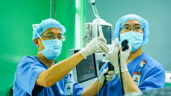 Phó Giáo sư, Tiến sĩ Lê Thượng Vũ (bên trái) thực hiện thủ thuật nội soi phế quản siêu âm sinh thiết.