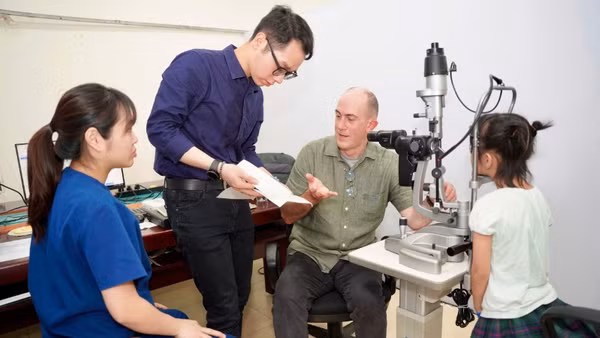 Tiến sĩ Timothy Robert Fricke,Giám đốc Nghiên cứu và Giáo dục tại Viện Nghiên cứu Thị giác Quốc gia, Trường Cao đẳng Khúc xạ Nhãn khoa Úc, đồng thời là Giáo sư danh dự Đại học Y Hà Nội khám cho em nhỏ.