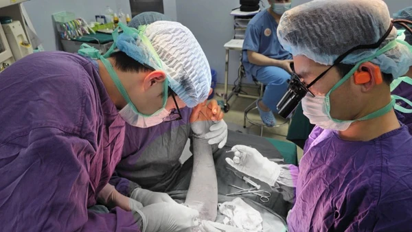 Bác sĩ tiến hành phẫu thuật trồng lại cánh tay đứt rời cho người bệnh. 