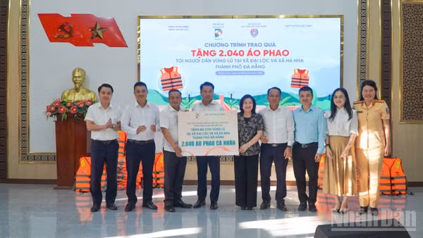 Lãnh đạo Bộ Nội vụ và Báo Dân Trí trao bảng tượng trưng tặng 2.040 áo phao cho người dân hai xã Đại Lộc và Hà Nha. (Ảnh: QV)