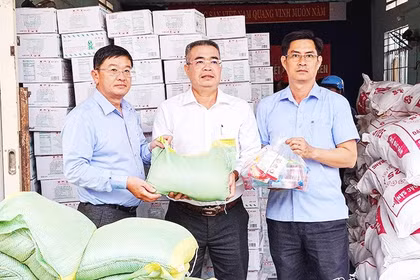 Nhà báo Lê Hoàng Triều (bên trái) trao quà hỗ trợ địa phương bị ảnh hưởng bởi mưa lũ.