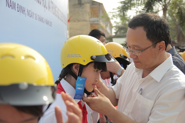 Đại diện lãnh đạo Ủy ban ATGT quốc gia tặng mũ bảo hiểm cho học sinh tiểu học tại tỉnh Nam Định. 
