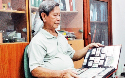 Ông Phùng Ðại Hùng bên bộ sưu tập tem.