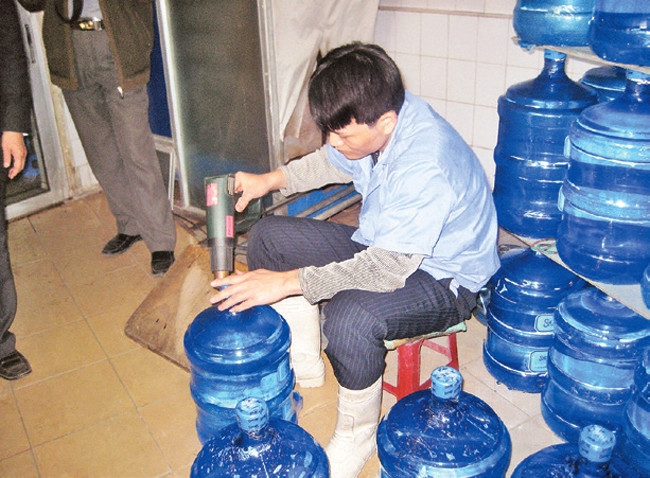 Đóng bình nước một cách thủ công, không tuân thủ quy định vệ sinh tại một cơ sở cung cấp nước "tinh khiết".