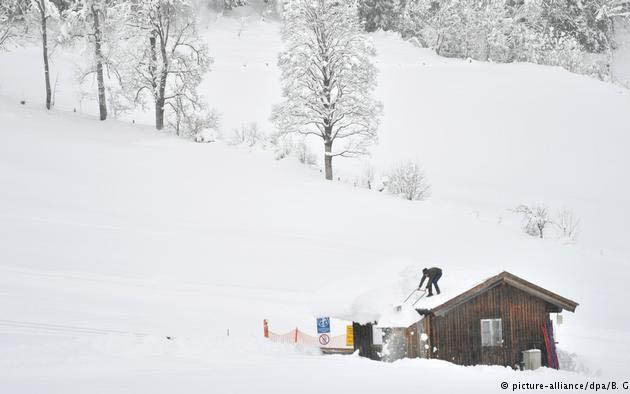 Người dân cào tuyết trước cửa nhà (ảnh: DW)