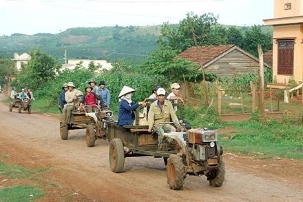 Người dân ở xã Thuận An, huyện Đác Mil điều khiển xe máy kéo nhỏ chở người đi rẫy.