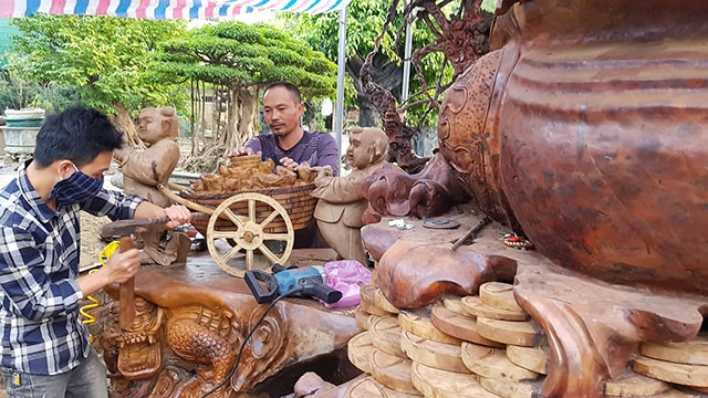 Nghệ nhân gỗ lũa Trịnh Thế Hưng hướng dẫn học trò bên tác phẩm “Cóc kiện trời”.