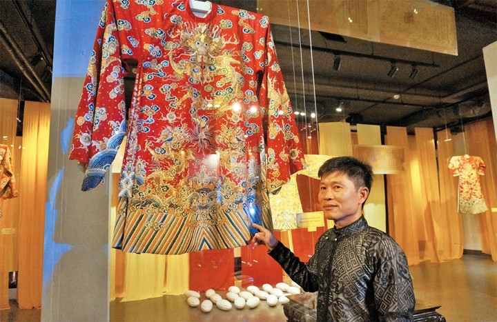 Nghệ nhân Nhân dân Vũ Văn Giỏi bên chiếc long bào phục chế.