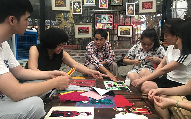 Họa sĩ Đặng Thị Khuê (thứ hai từ trái sang) và anh Lê Việt Cường (thứ ba từ trái sang) hướng dẫn các học viên người khuyết tật làm tranh ghép vải.