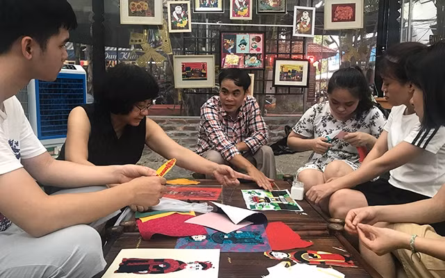 Họa sĩ Đặng Thị Khuê (thứ hai từ trái sang) và anh Lê Việt Cường (thứ ba từ trái sang) hướng dẫn các học viên người khuyết tật làm tranh ghép vải.