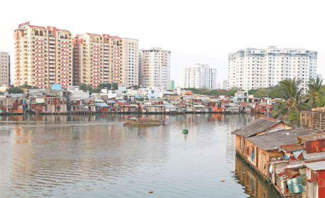 Những ngôi nhà “ổ chuột” ven kênh Tẻ, phía sau là “rừng” cao ốc mới.