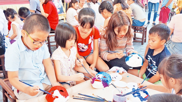 Các em thiếu nhi trang trí mặt nạ giấy bồi trong Hội sách Trăng tròn tại Phố sách Hà Nội.