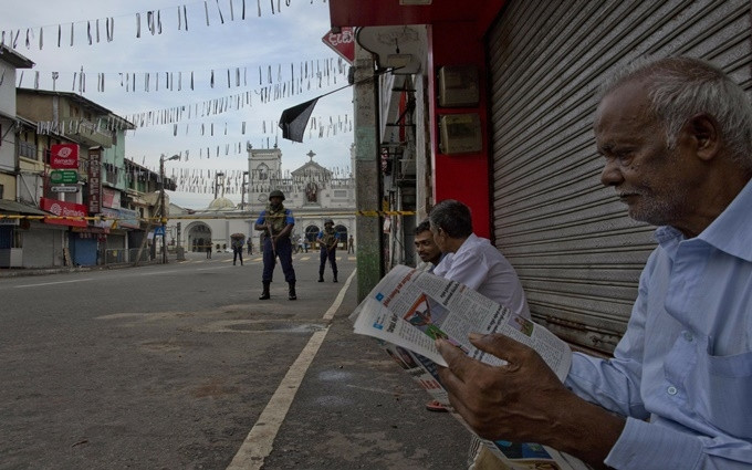 Người đàn ông đọc báo bên ngoài nhà thờ Đền thờ Thánh Anthony đang được bảo vệ nghiêm ngặt. (Ảnh: AP)