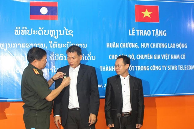 Đại tá Khăm-muôn Lương-văn-la gắn Huy chương Lao động của Thủ tướng Lào cho cán bộ, chuyên gia Việt Nam. 