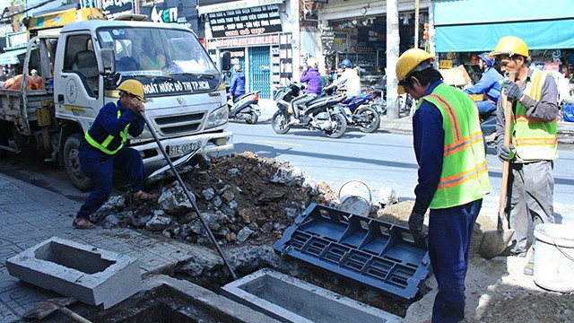 Công nhân đang lắp nắp hố ga trên đường Lê Văn Thọ (quận Gò Vấp).