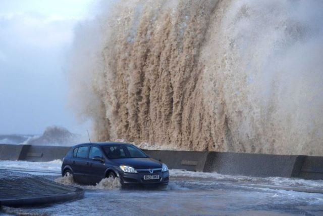 Xe ô-tô di chuyển trên một con đường bị ngập. (Ảnh: Reuters)