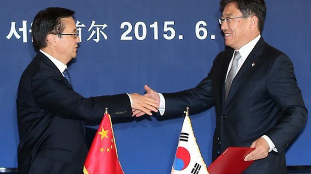 Bộ trưởng Thương mại Hàn Quốc Yoon Sang-jick (bên phải) và người đồng cấp Trung Quốc Gao Hucheng bắt tay sau khi chính thức ký Hiệp định thương mại tự do Trung Quốc-Hàn Quốc, tại một khách sạn ở Thủ đ