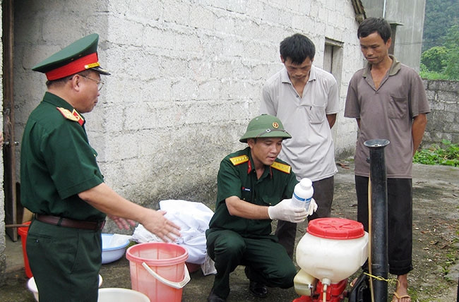 Cán bộ quân y hướng dẫn người dân pha hóa chất diệt côn trùng trong phòng, chống dịch bệnh.