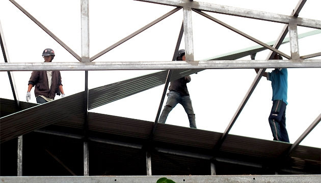 Công nhân tháo dỡ mái che xưởng hạt điều của Công ty TNHH Long Việt xây dựng trái phép trong khu dân cư xã An Chấn, huyện Tuy An.