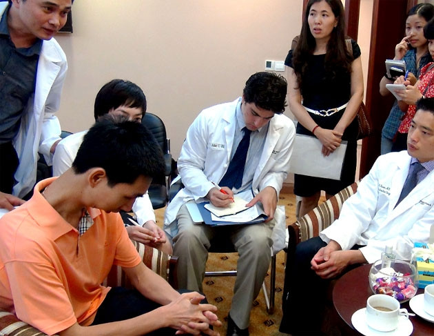 Bệnh nhân không há miệng được (áo mầu cam, bên trái) sau khi được đoàn chuyên gia phẫu thuật và nay đã có thể cử động được các hàm.