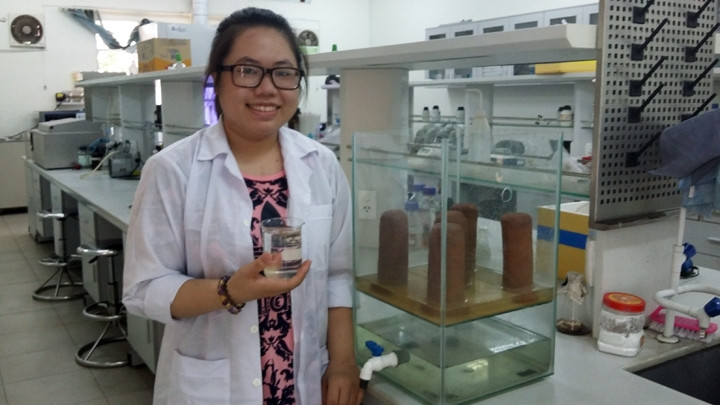 Nguyễn Hoàng Hải Trà bên sản phẩm màng lọc nước từ phế thải bùn đỏ và rác hữu cơ.