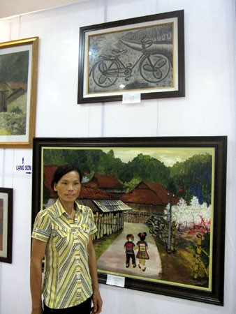 Chị Thậm bên bức tranh “Xe đạp” tại Triển lãm mỹ thuật khu vực Tây Bắc - Việt Bắc đang diễn ra tại Bắc Cạn.