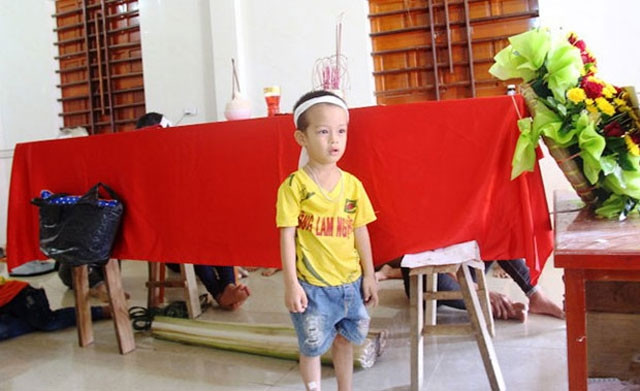 Con trai bốn tuổi của nạn nhân Trần Văn Sáng, xã Thanh Khê, huyện Thanh Chương ngơ ngác bên quan tài của bố.