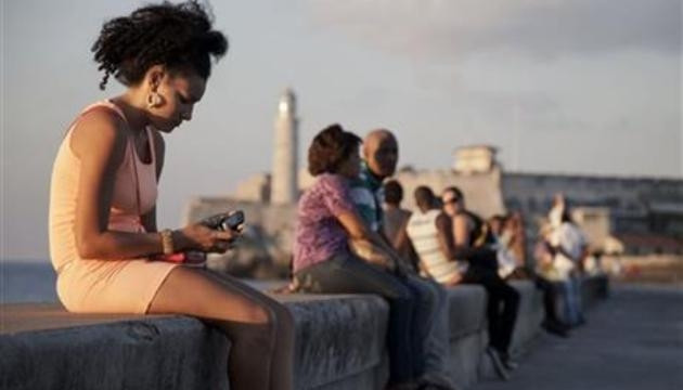 Trong bức ảnh chụp ngày 11-3-2014, một người phụ nữ sử dụng điện thoại di động của mình khi ngồi bên bờ biển Malecon, Havana, Cuba. (Ảnh: AP)