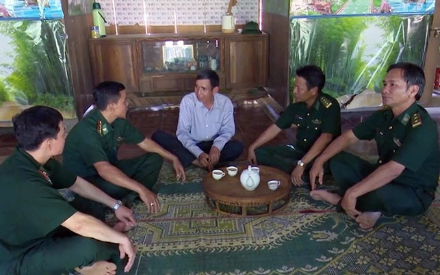 Già làng Alăng Nhứch (người ở giữa) trao đổi công việc với cán bộ, chiến sĩ Ðồn Biên phòng La Êê.