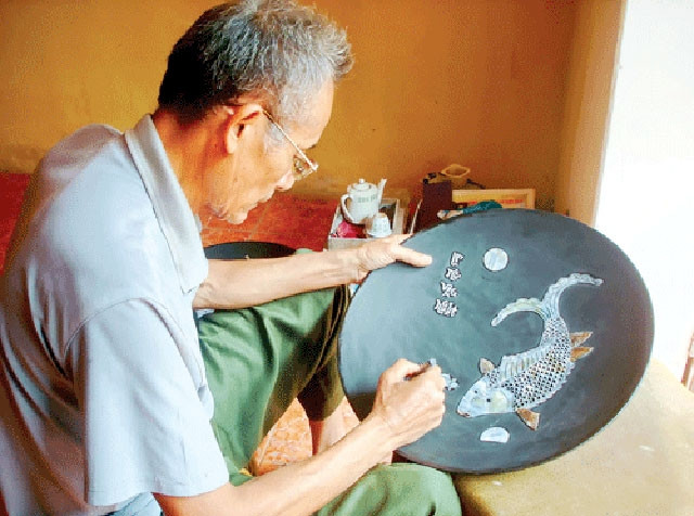 Nghệ nhân khảm trai đang chế tác sản phẩm. Ảnh: HOÀNG BÍCH