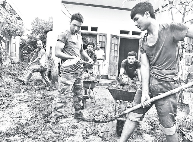 Chiến sĩ Quân khu 2 giúp dân dọn dẹp nhà sau lũ.