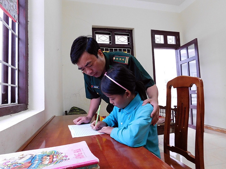 Thượng tá Phạm Ngọc Thủy hướng dẫn cháu Thò Thị Dính trong giờ học tại Ðồn Biên phòng Lũng Cú.