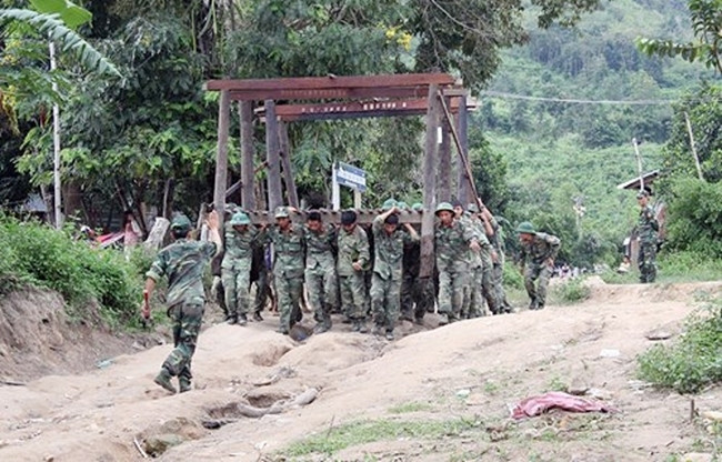 Cán bộ, chiến sĩ Sư đoàn 2 (Quân khu 5) giúp người dân làng Brang, xã Đăk Pling, huyện Kông Chro (Gia Lai) chuyển nhà đến nơi ở mới. Ảnh: QUANG HỒI