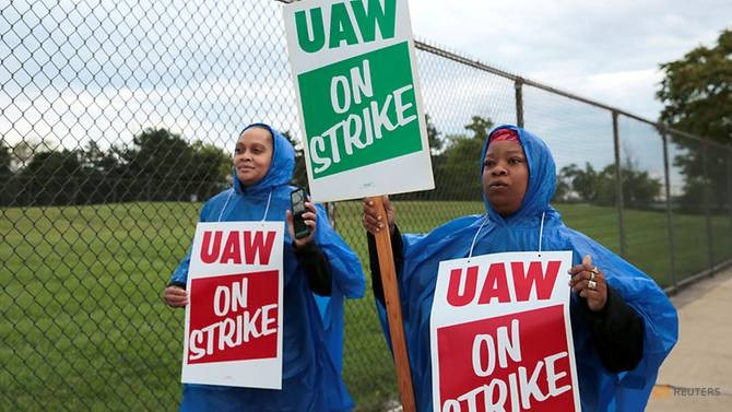 Các công nhân ngành ô tô cầm biểu ngữ bên ngoài nhà máy GM ở TP Detroit (Ảnh: Reuters)