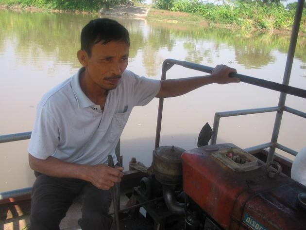 Ông Trần Văn Khương điều khiển đò chở khách qua sông.