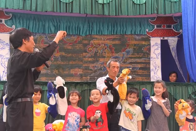 Nghệ nhân hướng dẫn các bé múa rối cạn. (Ảnh: BTDTHVN)