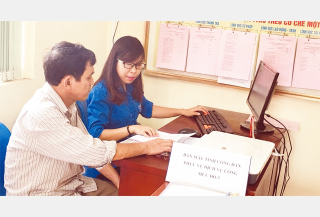 Tình nguyện viên hỗ trợ người dân đăng nhập hệ thống dịch vụ công trực tuyến mức độ 3 tại UBND phường Thượng Cát (huyện Bắc Từ Liêm).