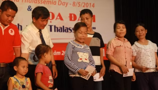 Em Phan Thị Vân (áo xanh kẻ) cùng các bệnh nhân khác nhận quà của các bác sĩ. 