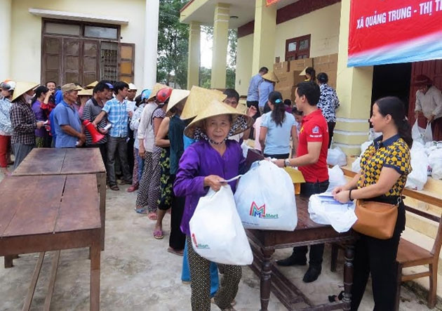 Chiều 26-10, người dân vùng lũ Quảng Trung, thị xã Ba Đồn, tỉnh Quảng Bình xếp hàng nhận quà cứu trợ.