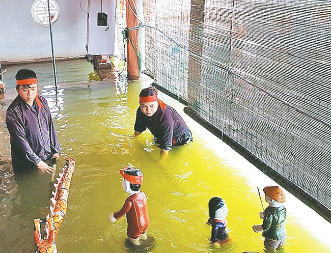 Anh Nguyễn Thế Nghị chuẩn bị cho một tiết mục rối nước trong buồng trò. Ảnh: ĐINH THANH