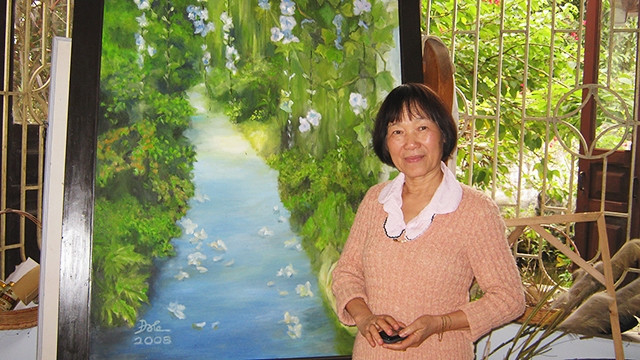 Nhà văn Đoàn Lê bên một bức tranh trong ngôi nhà bên biển.