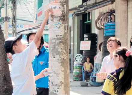 Các em nhỏ xóa quảng cáo, rao vặt trên các tuyến đường.