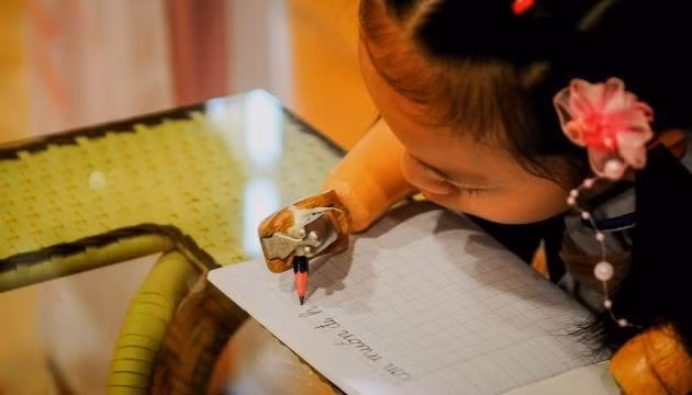 Bé Nguyễn Linh Chi nắn nót viết dòng chữ "Con muốn đi học".