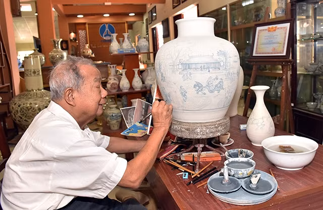 Nghệ nhân Hạ Bá Định vẽ trên bình gốm Chu Đậu. Ảnh: ĐĂNG ANH