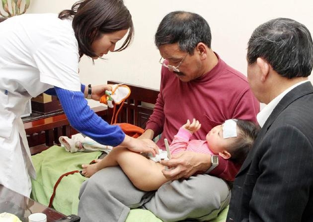 Bác sĩ đến tận nhà để cấp cứu trẻ bị sốt.  Ảnh: DƯƠNG NGỌC