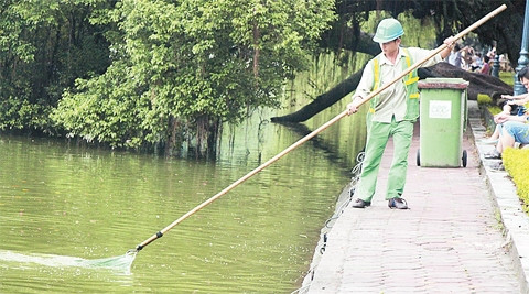 Công nhân Công ty Môi trường đô thị Hà Nội vớt rác tại Hồ Hoàn Kiếm. Ảnh: LÊ DŨNG